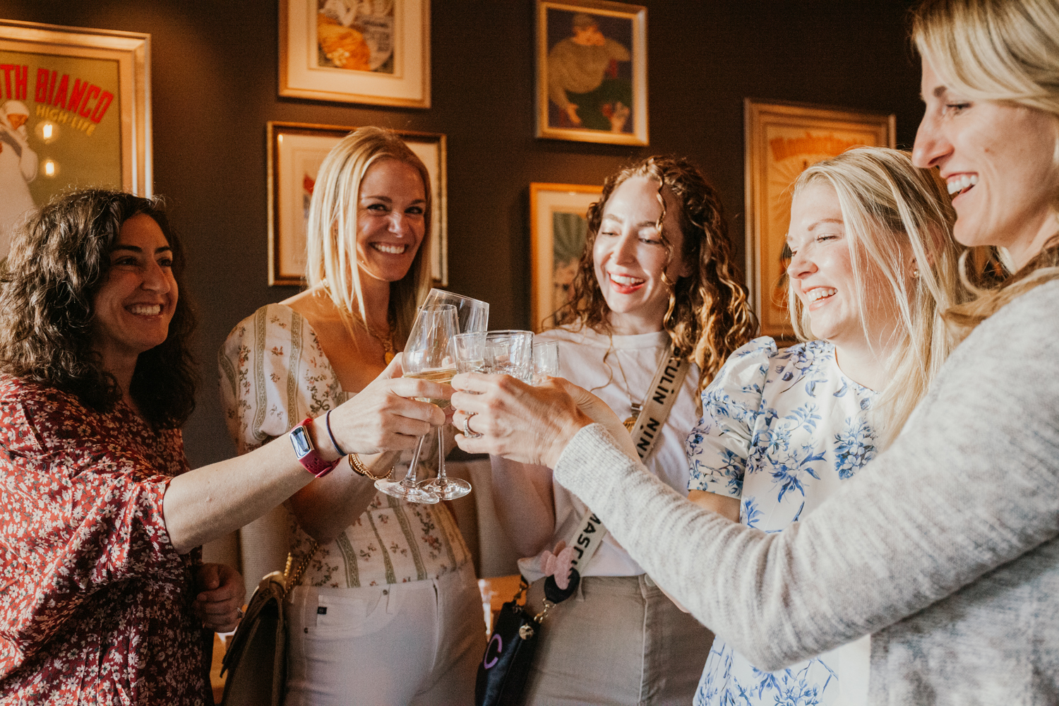 Image of five women clinking wine glasses